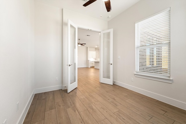 empty room with light wood-style flooring, french doors, baseboards, and ceiling fan