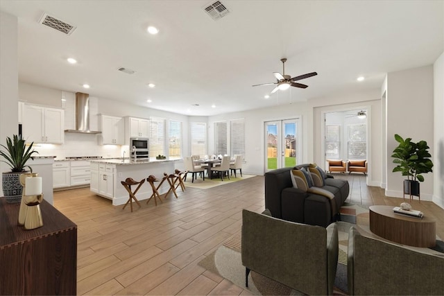 living room with light wood finished floors, visible vents, recessed lighting, and french doors