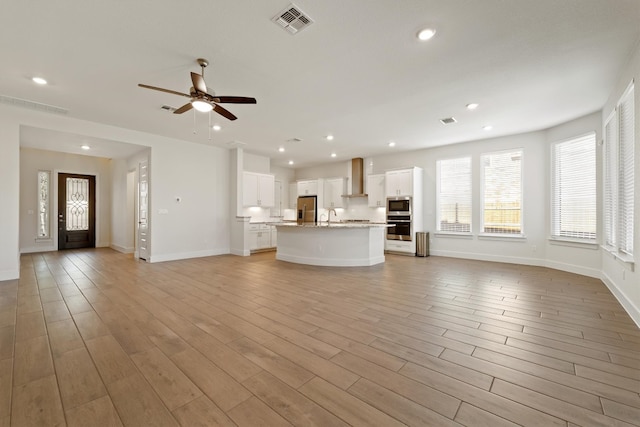 unfurnished living room with a ceiling fan, recessed lighting, light wood-style floors, and visible vents