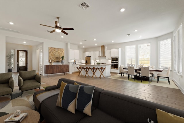 living room with recessed lighting, visible vents, and light wood-style flooring