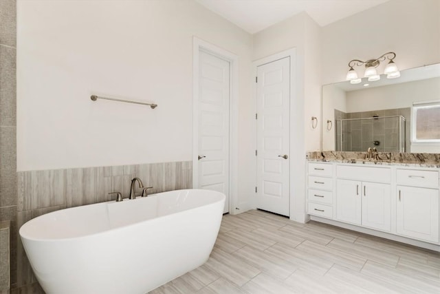 full bathroom featuring a soaking tub, a wainscoted wall, vanity, and a shower stall