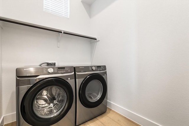 clothes washing area with light wood-style flooring, baseboards, washing machine and dryer, and laundry area