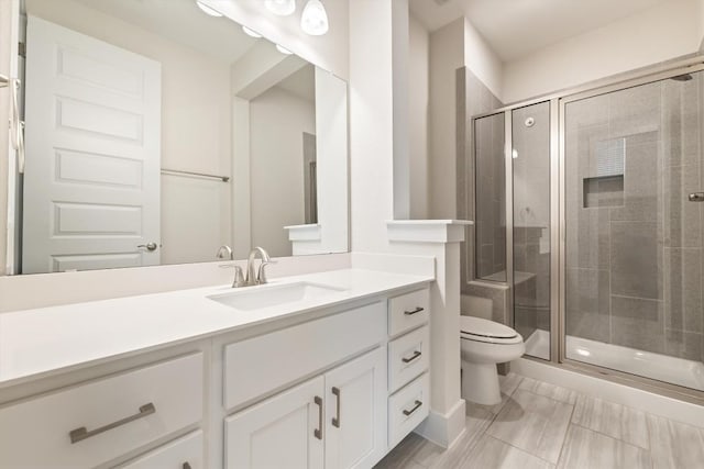 bathroom with toilet, a stall shower, and vanity