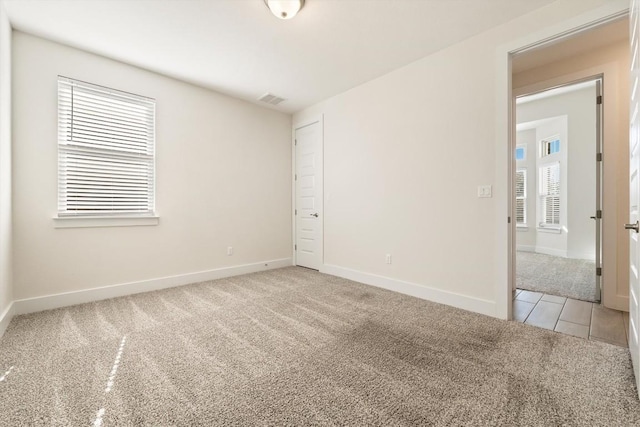 unfurnished room featuring light carpet, visible vents, and baseboards