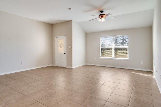 empty room featuring lofted ceiling, light tile patterned flooring, a ceiling fan, and baseboards