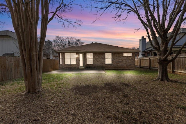 rear view of property with a patio, brick siding, and a fenced backyard