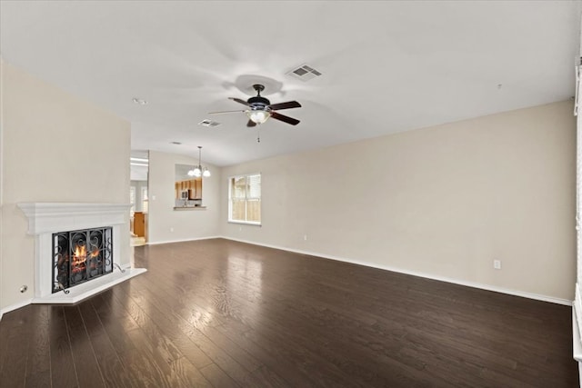 unfurnished living room featuring visible vents, dark wood-type flooring, ceiling fan with notable chandelier, a warm lit fireplace, and lofted ceiling