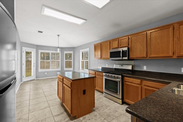 kitchen featuring visible vents, a kitchen island, decorative light fixtures, brown cabinets, and appliances with stainless steel finishes