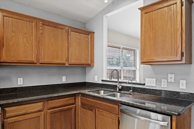 kitchen featuring stainless steel dishwasher, dark stone countertops, brown cabinets, and a sink