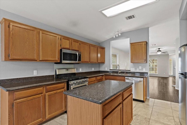 kitchen featuring visible vents, a sink, dark stone countertops, stainless steel appliances, and lofted ceiling