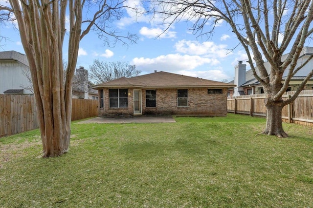 back of property with a yard, brick siding, a fenced backyard, and a patio area