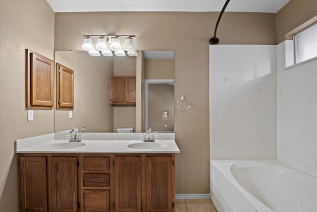 bathroom featuring double vanity, a sink, a garden tub, toilet, and tile patterned floors