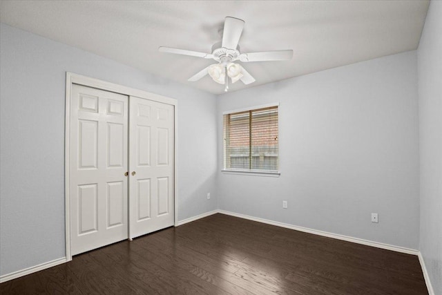 unfurnished bedroom featuring dark wood-type flooring, baseboards, and a closet