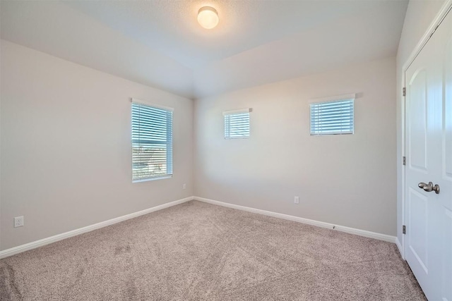 empty room with baseboards, carpet flooring, and vaulted ceiling