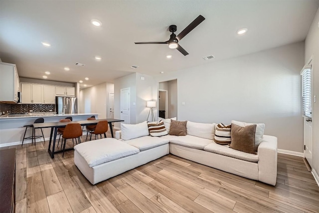 living area with light wood finished floors, visible vents, recessed lighting, and a ceiling fan