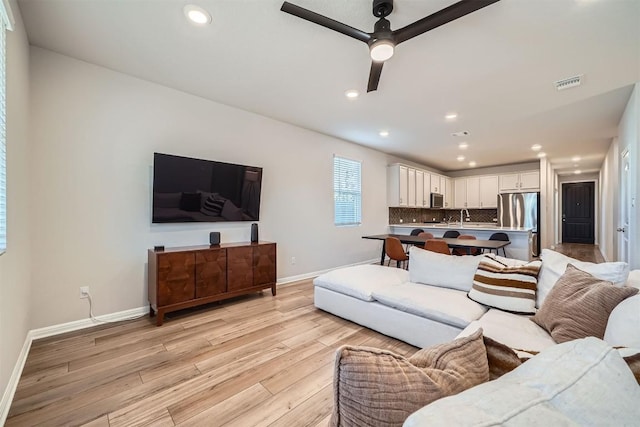 living area with a ceiling fan, baseboards, visible vents, recessed lighting, and light wood-type flooring