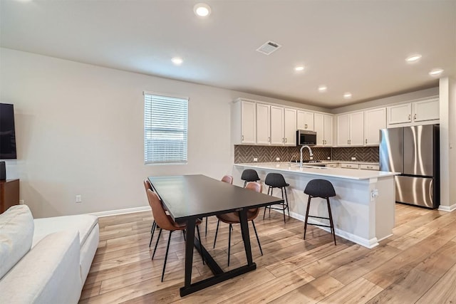 kitchen featuring visible vents, a sink, light wood-style floors, appliances with stainless steel finishes, and tasteful backsplash