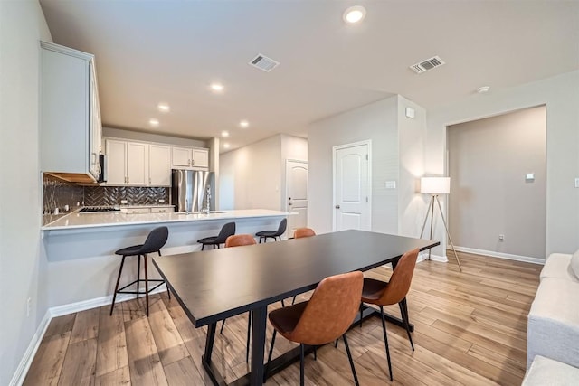 dining room featuring visible vents, light wood-style flooring, and baseboards