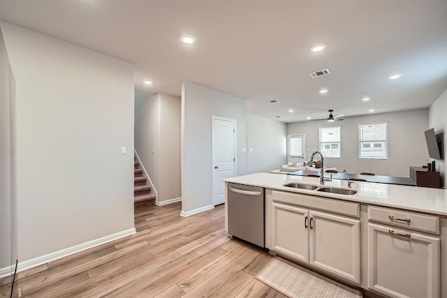 kitchen with visible vents, light wood finished floors, a sink, stainless steel dishwasher, and light countertops