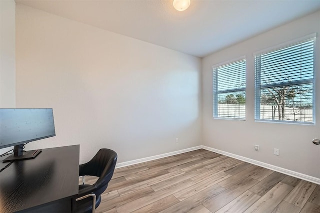 office space with baseboards and light wood-type flooring