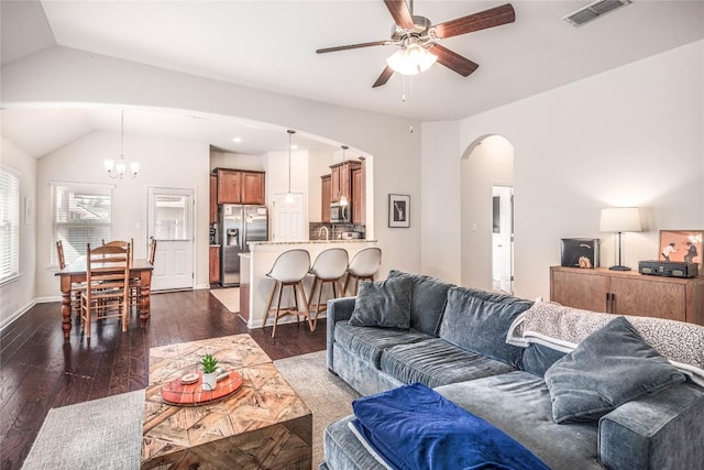 living room featuring visible vents, dark wood finished floors, vaulted ceiling, ceiling fan with notable chandelier, and arched walkways