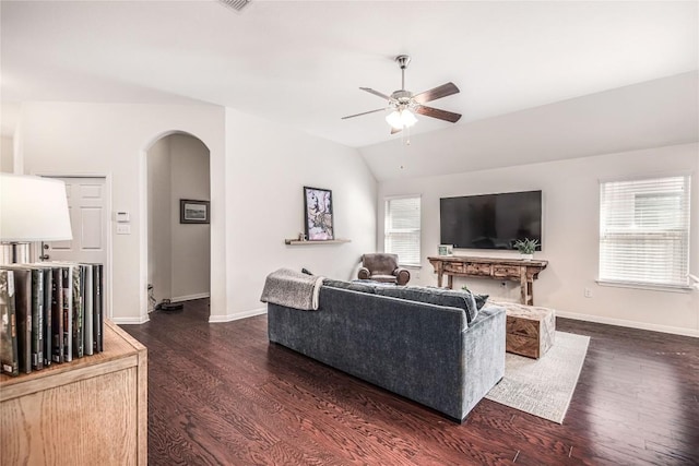 living room featuring arched walkways, dark wood-style floors, baseboards, and vaulted ceiling