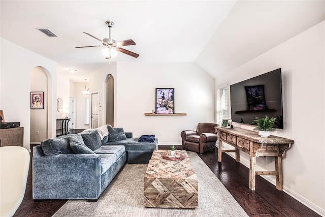 living area featuring wood finished floors, visible vents, baseboards, arched walkways, and vaulted ceiling