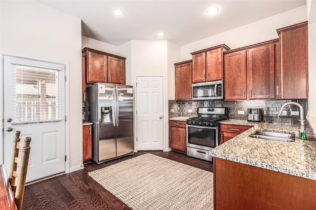 kitchen with tasteful backsplash, dark wood-type flooring, light stone counters, stainless steel appliances, and a sink