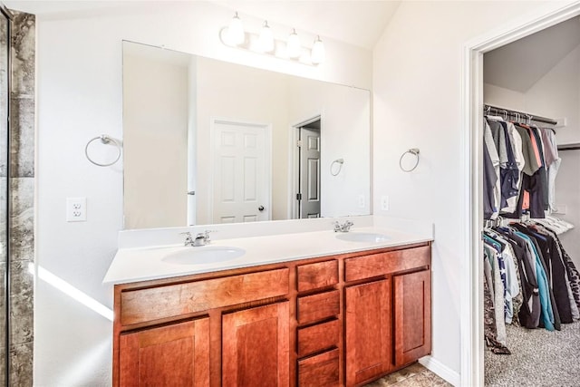 full bathroom with double vanity, a spacious closet, and a sink