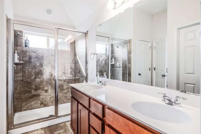 full bath featuring a sink, a stall shower, double vanity, and vaulted ceiling