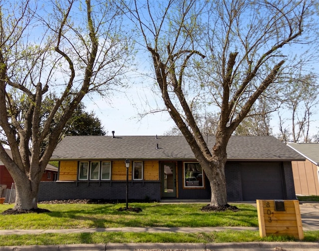 single story home with a front lawn, an attached garage, and brick siding