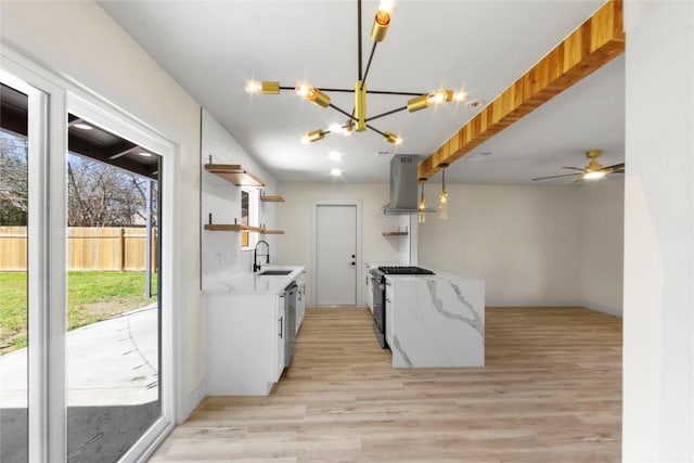 kitchen with stainless steel gas range, open shelves, a sink, light wood-type flooring, and island range hood