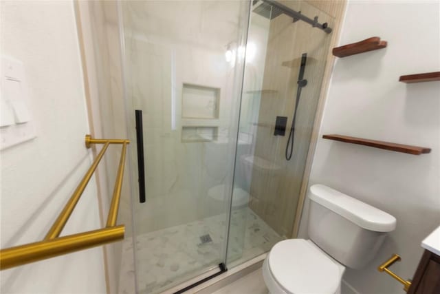 bathroom featuring a marble finish shower, toilet, and vanity