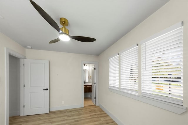 unfurnished bedroom featuring ceiling fan, baseboards, light wood-type flooring, and connected bathroom