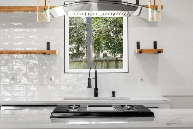 kitchen featuring backsplash, light stone countertops, and a sink