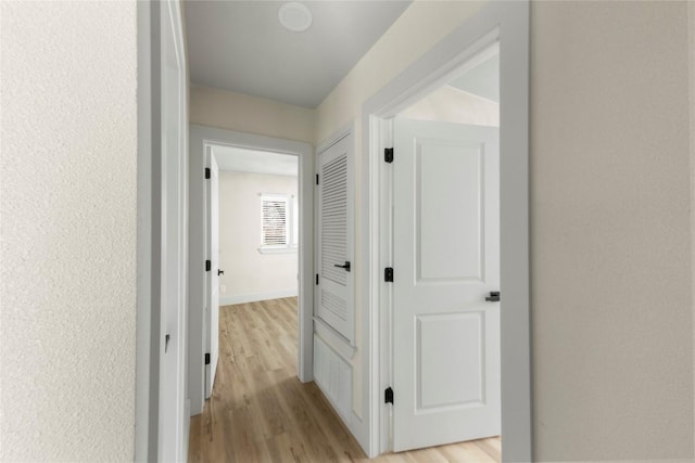 hall featuring baseboards and light wood-style flooring