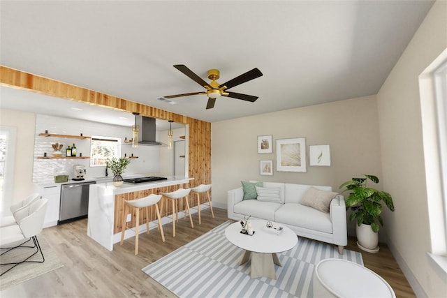 living area with ceiling fan, visible vents, baseboards, and light wood-style flooring