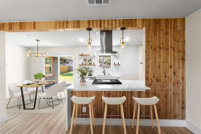 kitchen featuring open shelves, island exhaust hood, visible vents, and wood walls