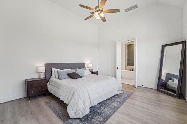 bedroom with visible vents, baseboards, light wood-style flooring, ensuite bathroom, and high vaulted ceiling