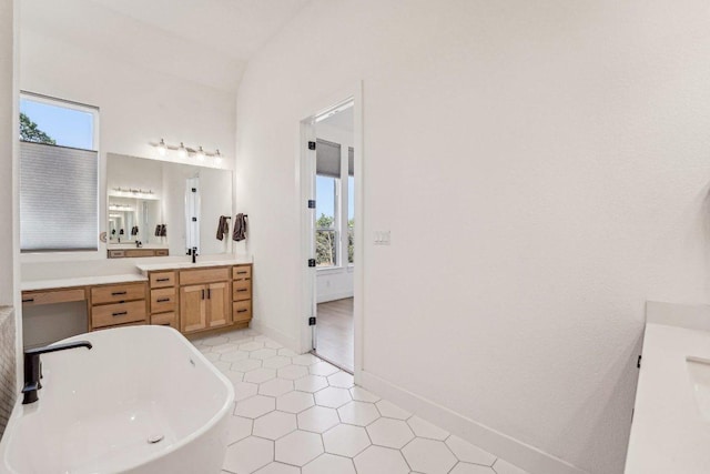 full bath featuring a soaking tub, vanity, and baseboards