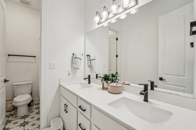 full bathroom with double vanity, visible vents, toilet, and a sink