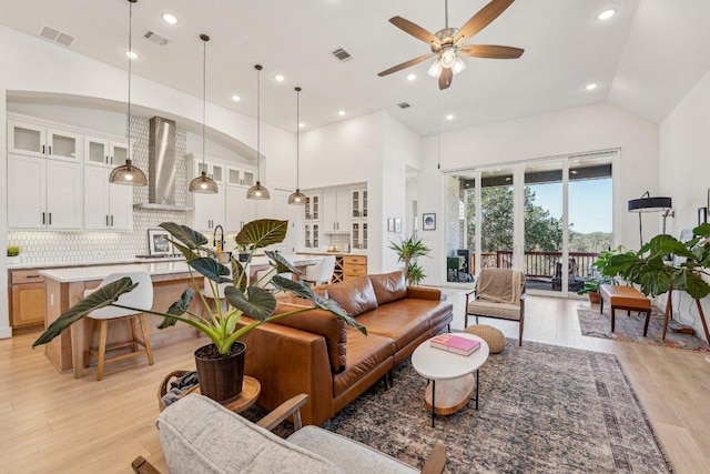 living room featuring high vaulted ceiling, visible vents, and light wood-type flooring