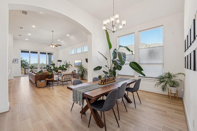 dining room with visible vents, arched walkways, light wood-style floors, and a high ceiling