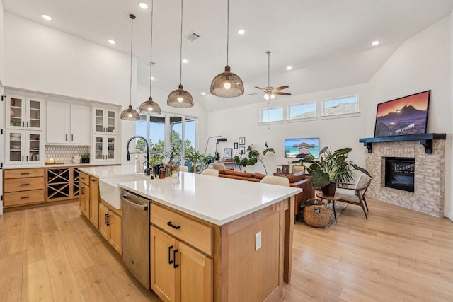 kitchen with stainless steel dishwasher, light countertops, light wood finished floors, and a sink