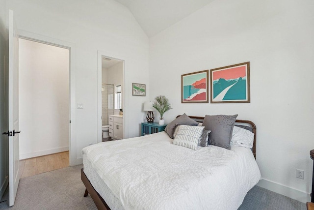 bedroom featuring baseboards, ensuite bath, and vaulted ceiling