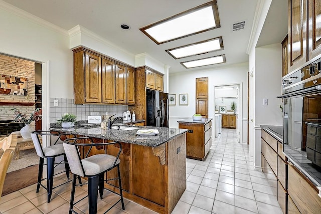 410 Rolling Green Dr, Lakeway, TX 78734 - kitchen featuring black refrigerator with ice dispenser, a center island, light tile patterned floors, a peninsula, and dark stone counters