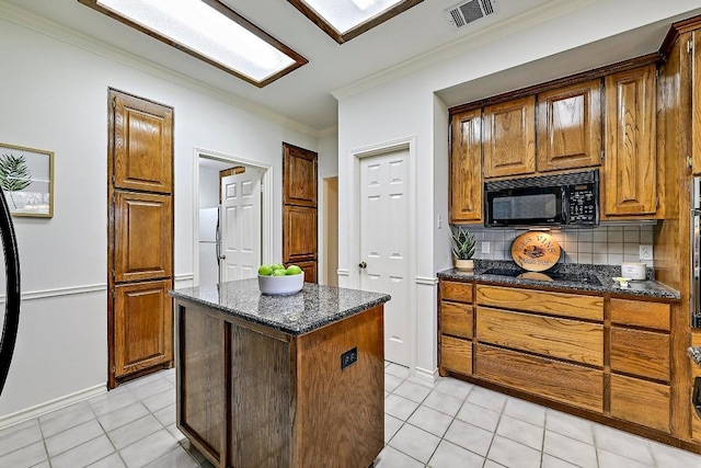 410 Rolling Green Dr, Lakeway, TX 78734 - kitchen with black microwave, backsplash, a kitchen island, ornamental molding, and light tile patterned floors