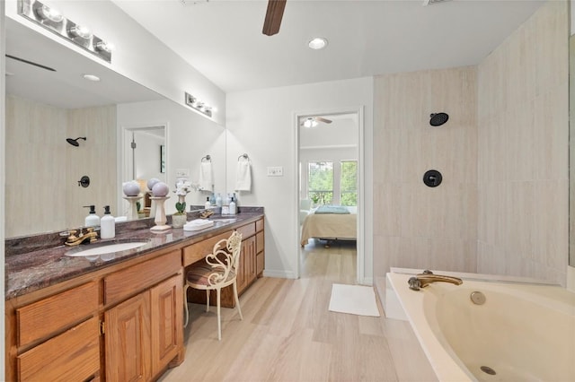 410 Rolling Green Dr, Lakeway, TX 78734 - ensuite bathroom with ceiling fan, a garden tub, double vanity, a tile shower, and wood finished floors