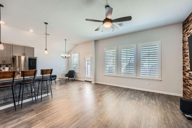 107 Lemuel Crawford Trl, Bastrop, TX 78602 - living room with a ceiling fan, dark wood-style flooring, lofted ceiling, baseboards, and a chandelier