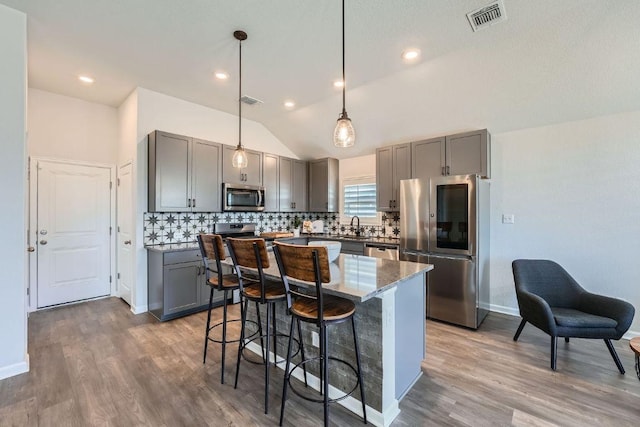 107 Lemuel Crawford Trl, Bastrop, TX 78602 - kitchen with appliances with stainless steel finishes, gray cabinets, lofted ceiling, light wood-type flooring, and tasteful backsplash